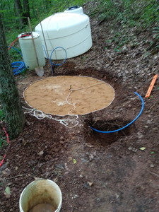 six foot circle marked off with rope
and filled with sand; a water tank is in the background and tools are
strewn around the cramped worksite