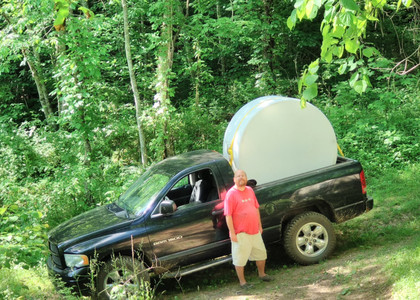 Joey standing in front of a black 4x4
pickup truck with a large white 550 gallon water tank on its side in the
bed and arching high above