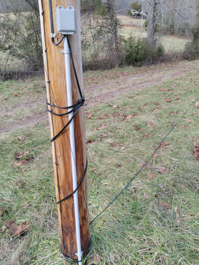 telephone pole with phone wire wrapped down it and extending across the ground