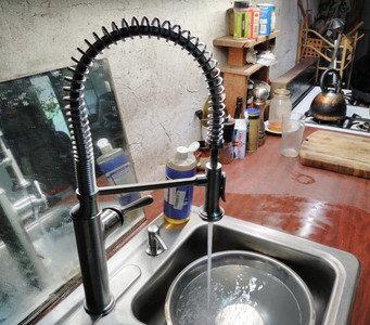 modern restaurant-style sprung arched
faucet with water flowing into the kitchen sink