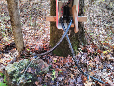 red cooler attached to a tree with a
pump in it. water is streaming out of one of the two pipes attached to it
