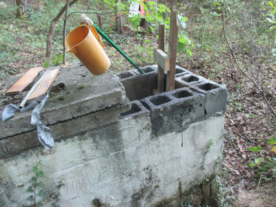 very narrow concrete
water tank with its concrete lid opened and a rough wooden ladder sticking
out of it